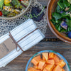 Linen napkin set on a table with bowls of grain salad, greens, and papaya