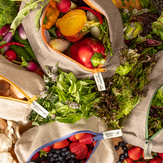 overhead view of leafy greens, vegetables, mushrooms, and berries inside the Ambrosia linen refrigerator bags
